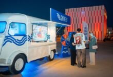 Van GNV blanc aux vagues bleues transformé en kiosque mobile, avec roue des cadeaux, à Tanja Marina Bay à Tanger
