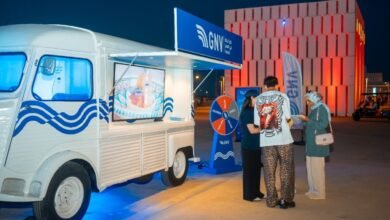 Van GNV blanc aux vagues bleues transformé en kiosque mobile, avec roue des cadeaux, à Tanja Marina Bay à Tanger